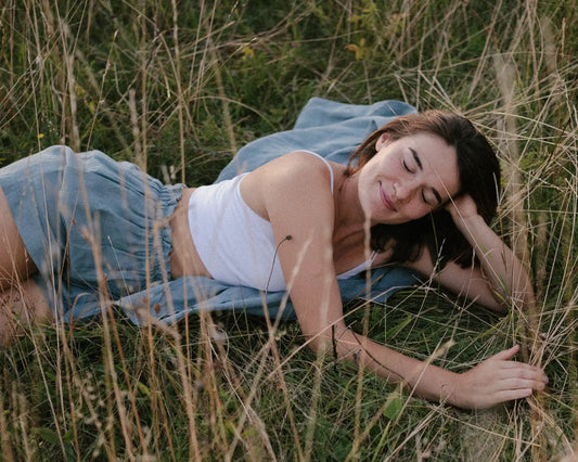 Woman lying in tall grass in natural light, relaxed summer mood