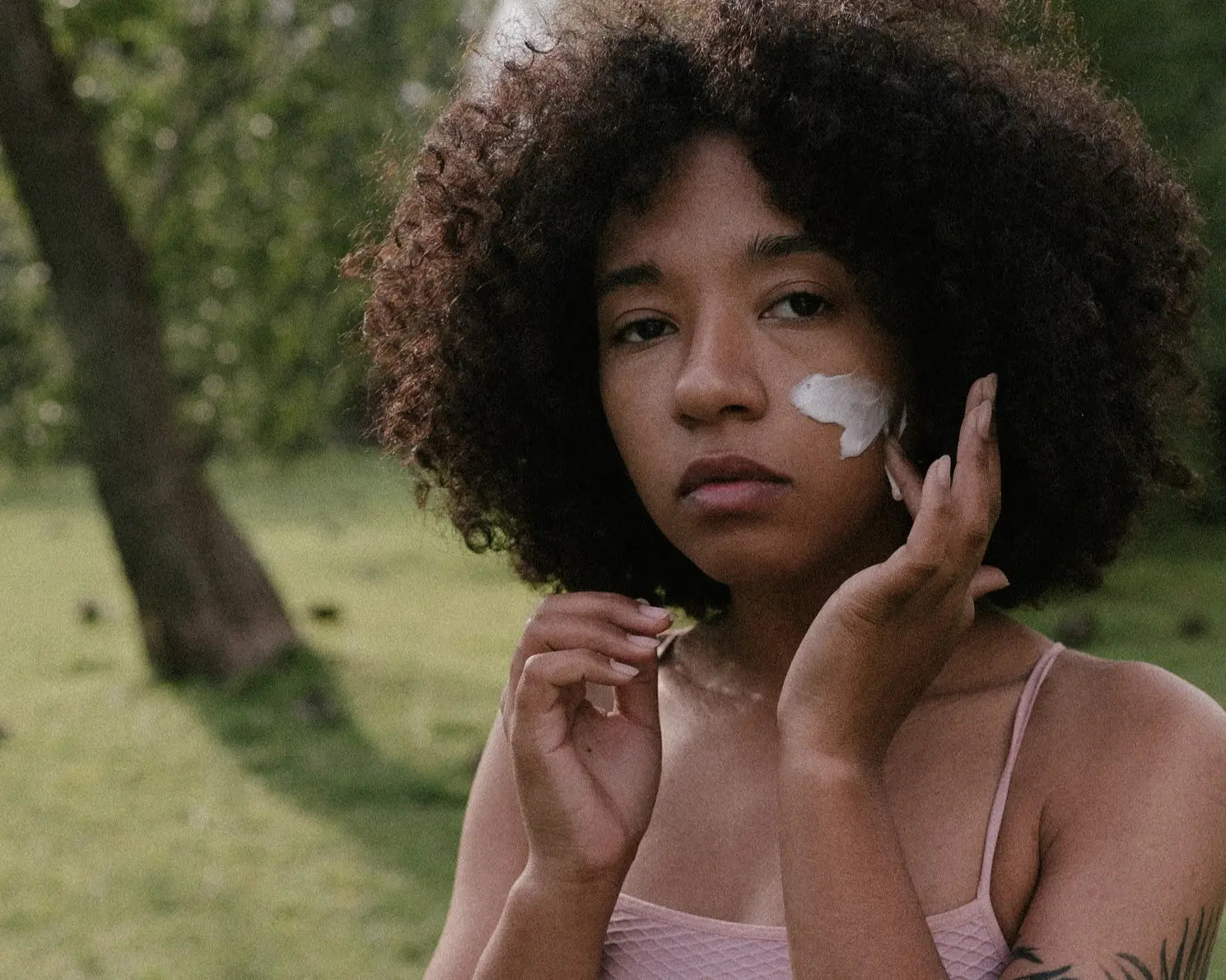 A close up of a black lady applying mineral sunscreen