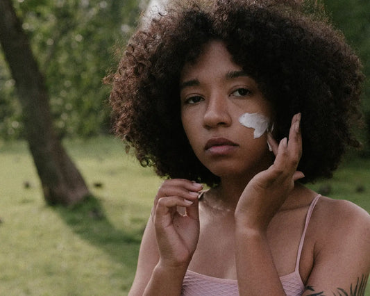 A close up of a black lady applying mineral sunscreen