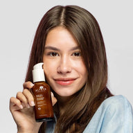 Woman holding a bottle of Alteya Luminous Rose Balancing Cleanser against a plain background
