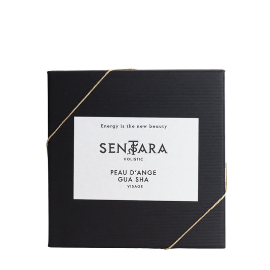 Black box containing an Angel Skin Gua Sha tool, wrapped with a gold ribbon and featuring Sentara Holistic branding, displayed on a white background.