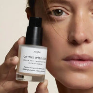 Person holding a bottle of On The Wild Side anti-blemish serum next to her face