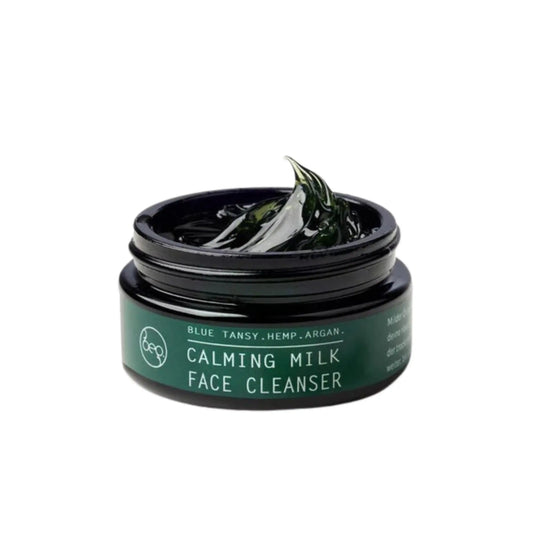 bepure Calming Milk face cleanser in an open dark green glass jar, with a dollop of deep green balm on top.