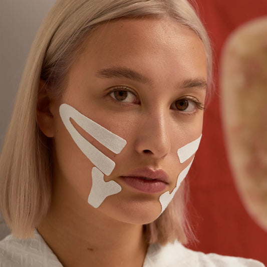 Woman wearing Lyfta white face lifting kinesiology tape on cheeks and chin