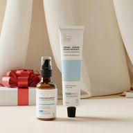 Skincare products including a bottle and tube on a neutral background with a gift box.