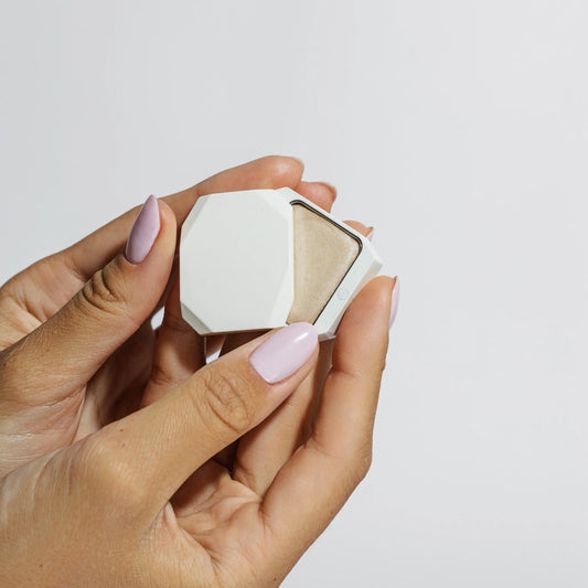 Close-up of hands holding open Uoga Uoga Luminous cream highlighter compact showing creamy texture