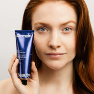 Femme rousse tenant le baume démaquillant Time to Detox de Demain Beauty près de son visage