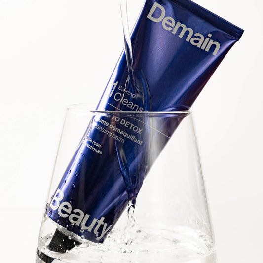 Tube du baume démaquillant Time to Detox de Demain Beauty dans un verre d'eau