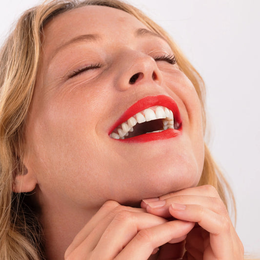 Woman with blonde hair smiling wearing Eclo 3-in-1 lip pencil Rouge Coquelicot 001