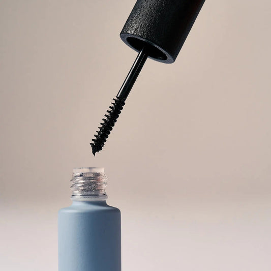 Eclo Black mascara open with black applicator brush on beige background