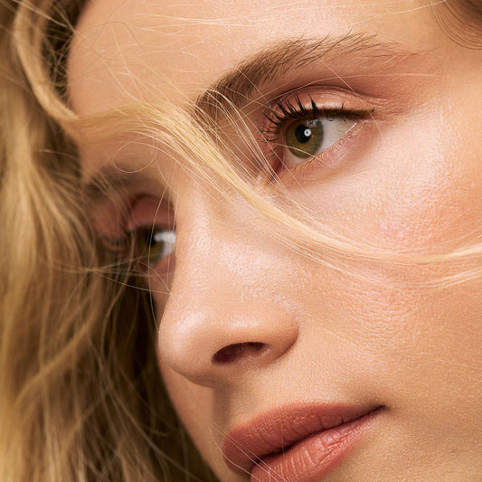 Close-up of person with blonde hair and green eyes wearing Eclo brown eyeliner pencil