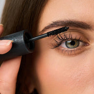 Close-up of person applying Eclo black mascara to eyelashes