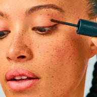 Close-up of person applying Eclo Warm Brown mascara to eyelashes