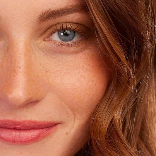 Close-up of person with red hair and blue eyes wearing Eclo Warm Brown mascara