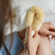 Person holding a natural bristle brush against a blurred background