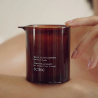 Amber candle jar labeled 'sense' held in a hand against a neutral background