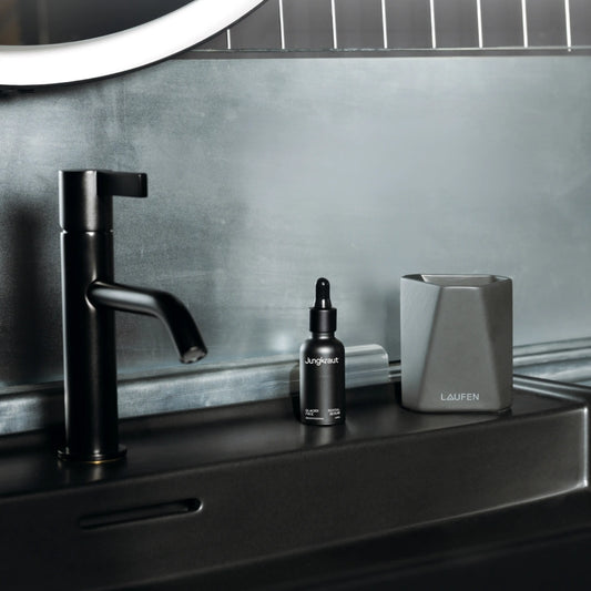 Jungkraut Glacier Revital Face Serum bottle placed in a dark blue, masculine-style bathroom setting.