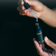 Close-up of Jungkraut Glacier Revital Face Serum in a man's hands against a dark background.