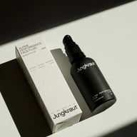 Jungkraut Alpine Performance Face Fluid in a black glass bottle with a nozzle dispenser, shown next to its outer cardboard box on a white background.