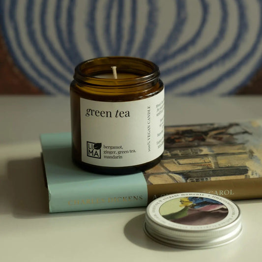 Green Tea Candle in a glass jar, surrounded by decorative elements with a blurred background