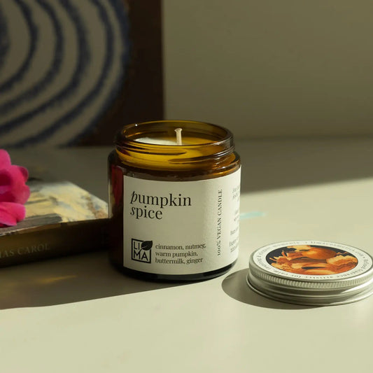 Pumpkin spice candle with a label on a neutral surface