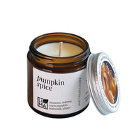 Pumpkin spice candle in a glass jar with a white label on a white background