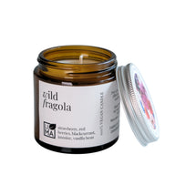 Candle in a glass jar labeled 'wild fragola' with a white background