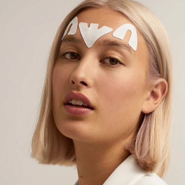 Woman wearing Lyfta forehead lifting kinesiology tapes on white background