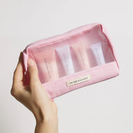 Hand holding On the Wild Side pink discovery kit bag with skincare mini products on a light background