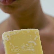 A close-up of a woman’s hand holding a Refeel Naturals soap bar.