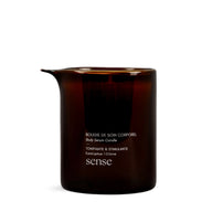 Amber glass jar containing a massage candle on a white background.