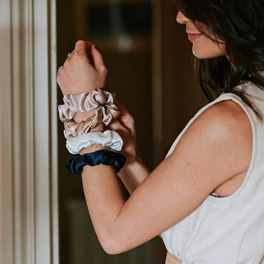 Woman holding multiple Hydra studio scrunchies on her wrist with a blurred background