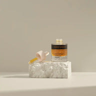 Open bottle of TEAM DR JOSEPH Age Repair Miracle Drops with its wooden pipette resting on a white stone block