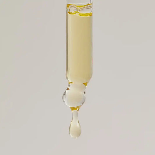 Glass pipette releasing a golden drop of TEAM DR JOSEPH Age Repair Miracle Drops face oil