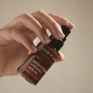 Hand pressing the pump of a TEAM DR JOSEPH Brightening Vitamin C Serum bottle