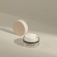 Open jar of TEAM DR JOSEPH Hyaluronic Repair Booster Cream showing the white cream texture, with the wooden lid resting behind it