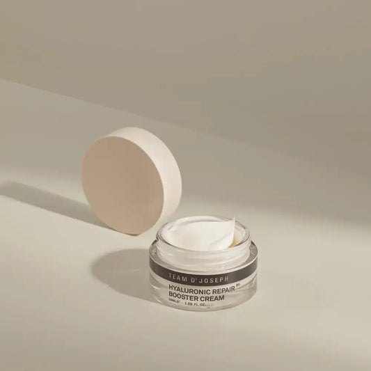 Open jar of TEAM DR JOSEPH Hyaluronic Repair Booster Cream showing the white cream texture, with the wooden lid resting behind it