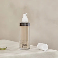 TEAM DR JOSEPH Purifying Cleansing Gel with a white pump, its cap set beside it on a linen-covered table