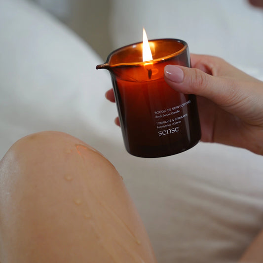 Hand holding a lit candle with a blurred background