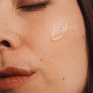 A close-up highlighting the texture of UMAÏ’s hydrating face cream on a woman’s cheek.