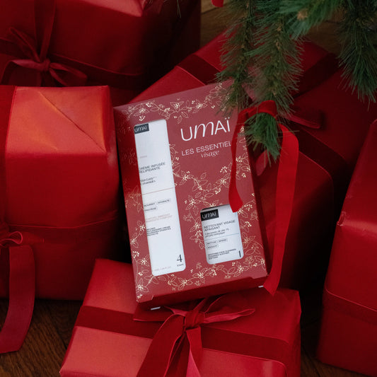 UMAÏ gift set displayed under a Christmas tree among red gift boxes.