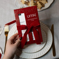 Umai Festive Gift Set - Les Essentiels held over a table setting with cookies in the background