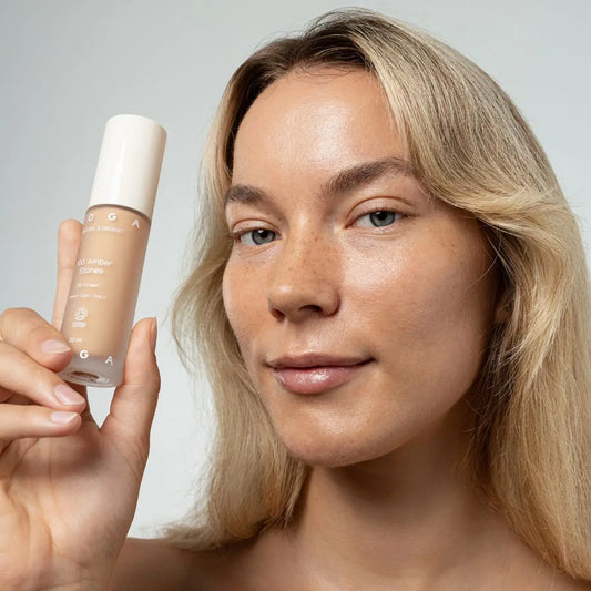 Woman holding a bottle of Uoga Uoga BB Cream with a neutral background