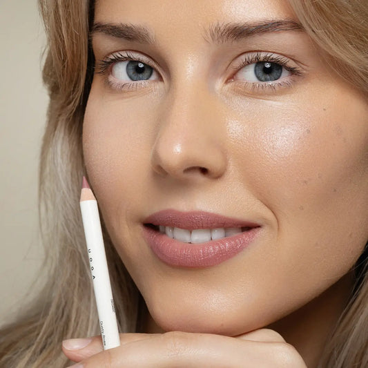 Woman holding Uoga Uoga Dusty rose lip pencil near her face against a white background
