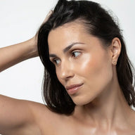 Woman with a neutral expression wearing Uoga Uoga Happy Ending powder on her skin against a plain background
