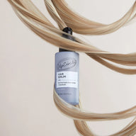 Hair serum bottle with wavy hair strands on a light background