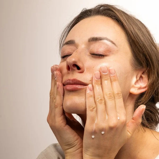 Woman massaging bepure Calming Milk cleansing balm into dry skin on her cheeks.