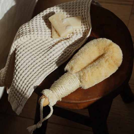 Natural body brush and washcloth on a wooden stool