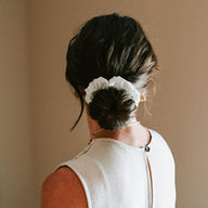 Person wearing Hydra Studio white scrunchie in bun hairstyle beige background lifestyle photo