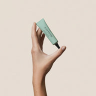 and holding On the Wild Side acne spot treatment paste tube on white background